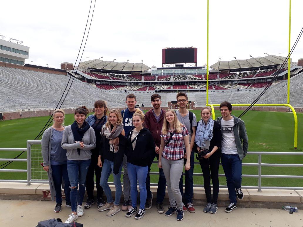 Eine kleine Gruppe Studenten, die am Rande eines Football-Feldes im leeren Stadion der Universität steht.