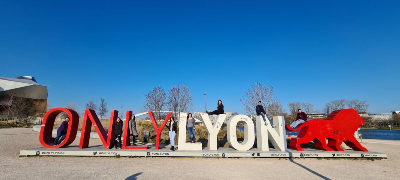 Studenten stehen in einer großen Plastik aus roten und weißen Buchstaben die Only Lyon buchstabieren