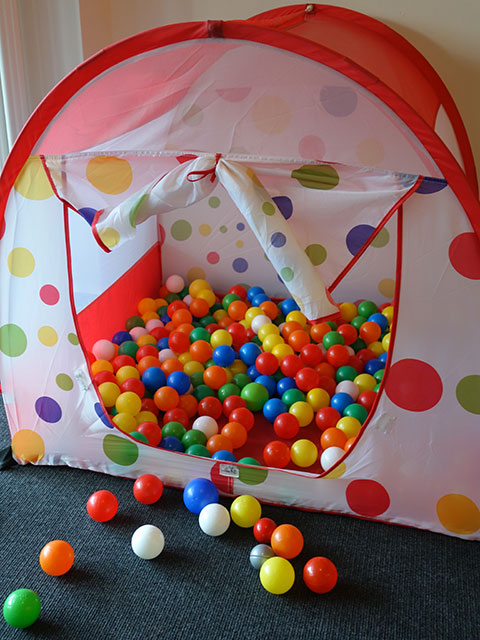 Ein Spielzelt im Spielzimmer mit vielen bunten Bällen.