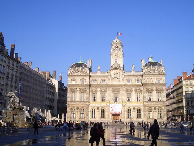 Auf dem Foto ist ein beeindruckend schöner Platz mit historischen Häuserfassaden und das Rathaus der Stadt Lyon abgebildet.