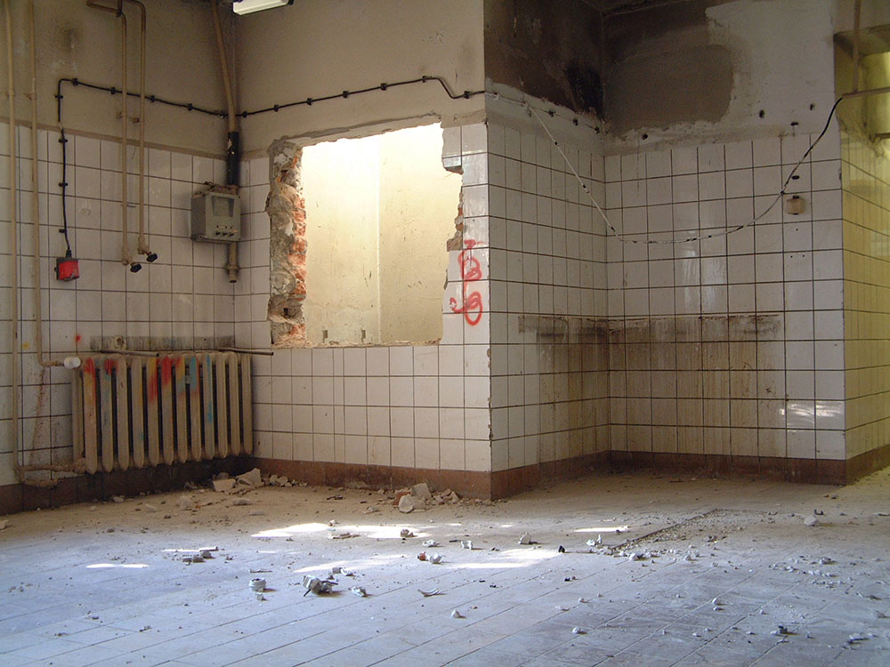 Foto einer leeren Küche. Die Wände sind teilweise eingerissen.