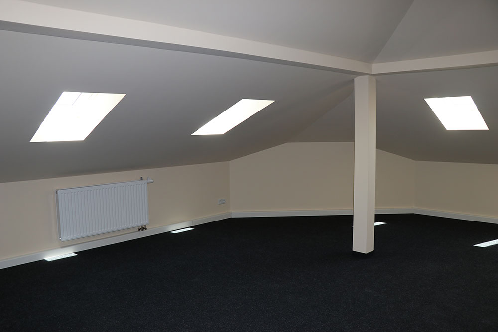 Foto der ausgebauten Proberaum im Dachgeschoss mit dunklem Teppich und Dachschrägen mit Fenstern