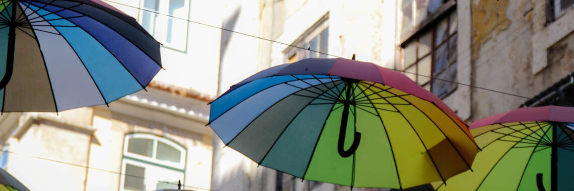 Mehrere bunte Schirme hängen in der Luft an einer Schnur